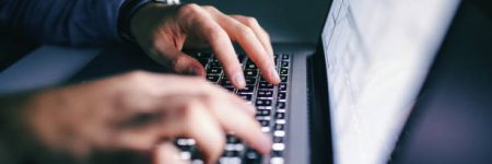 Close up of hands typing on laptop. Night work concept.